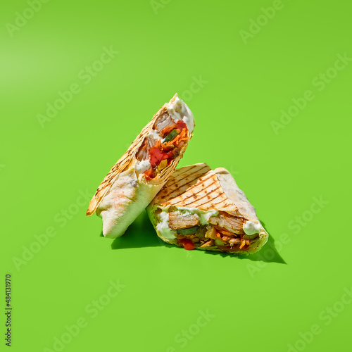 Shawarma with vegetables and meat on green background. Contemporary poster with shawarma. Doner kebab in minimal style. Street food concept. Junk food design. Minimalistic fast food menu.