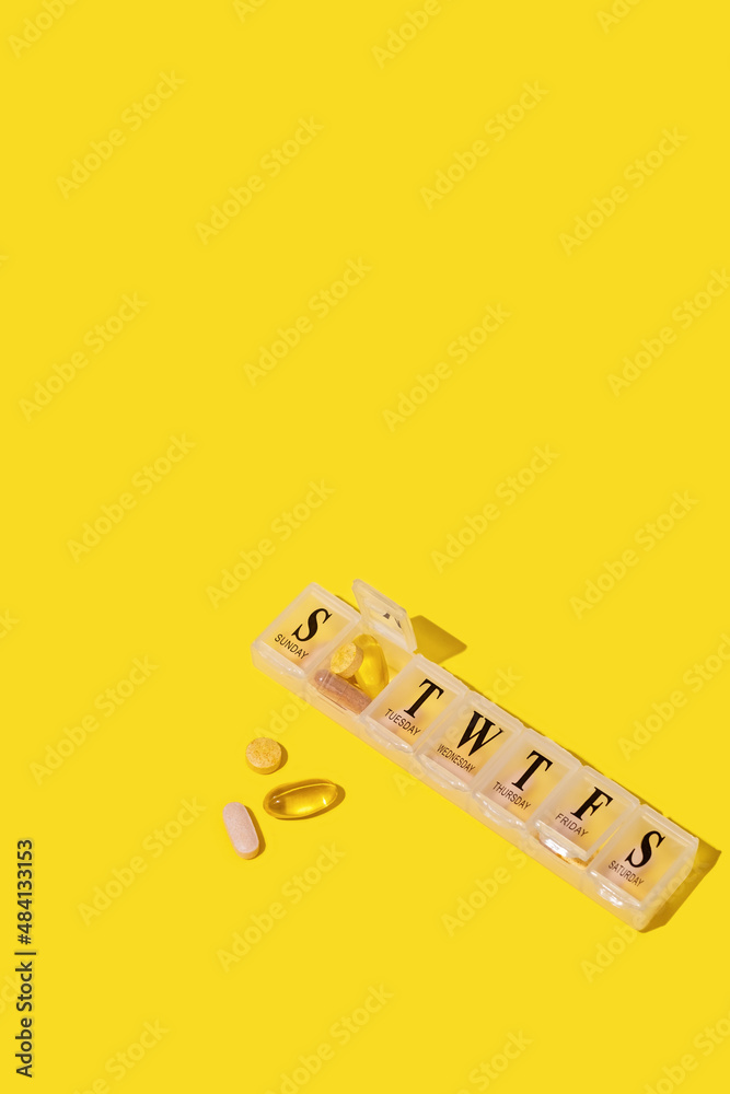 Pills organizer on yellow background.
Nutritional supplements and vitamins concept Pills organizer on yellow background.
Nutritional supplements and vitamins concept