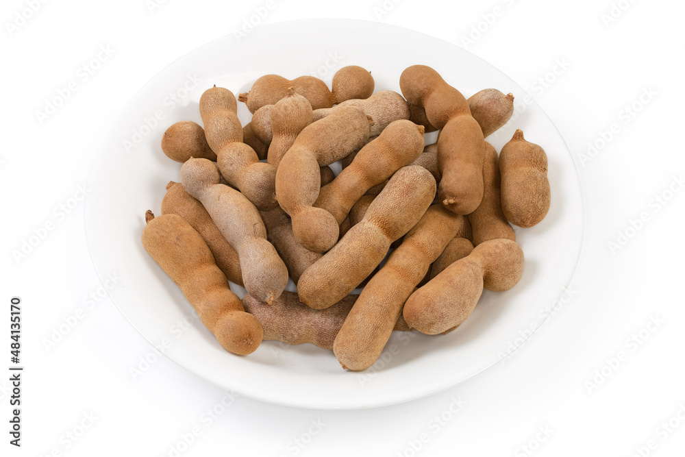 Fototapeta premium Ripe dry whole tamarind fruits on a white dish
