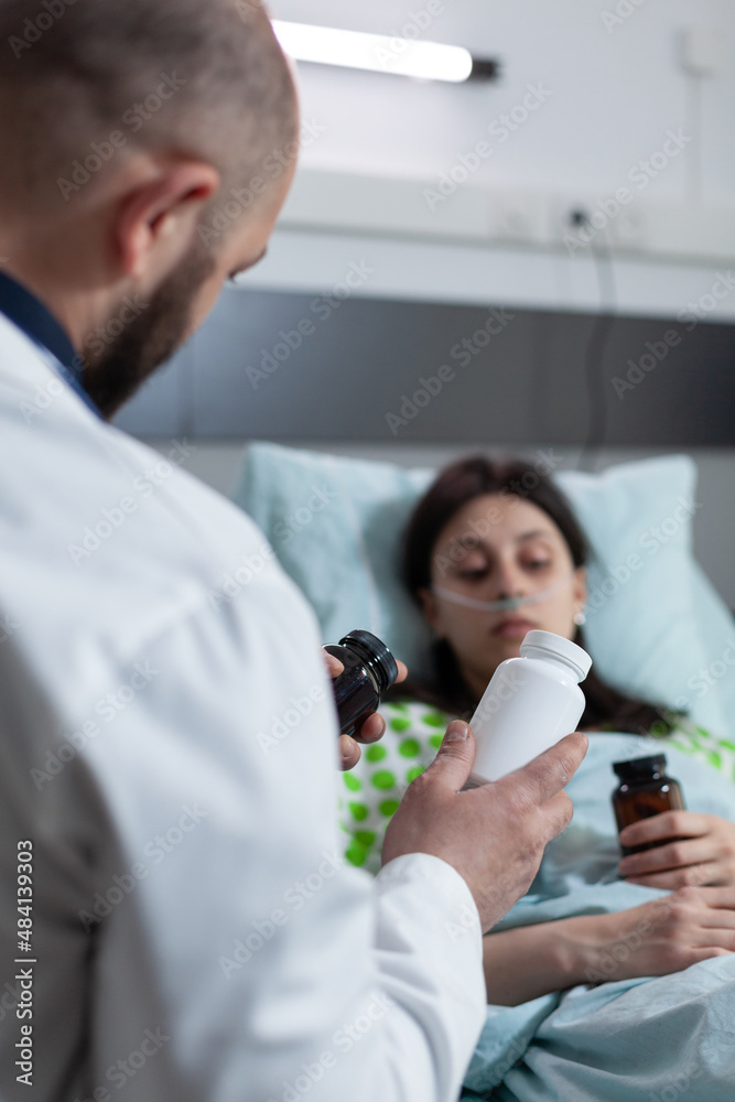Focus on prescription drugs medication bottle given by doctor to recovering patient after surgical intervention. Medic presenting alternative treatment to woman with low oxygen saturation. Focus on prescription drugs medication bottle given by doctor to recovering patient after surgical intervention. Medic presenting alternative treatment to woman with low oxygen saturation.