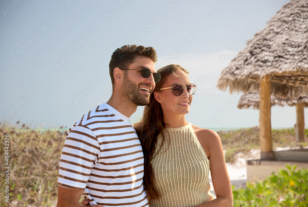 travel, tourism and people concept - happy couple in sunglasses over tropical beach background in french polynesia
