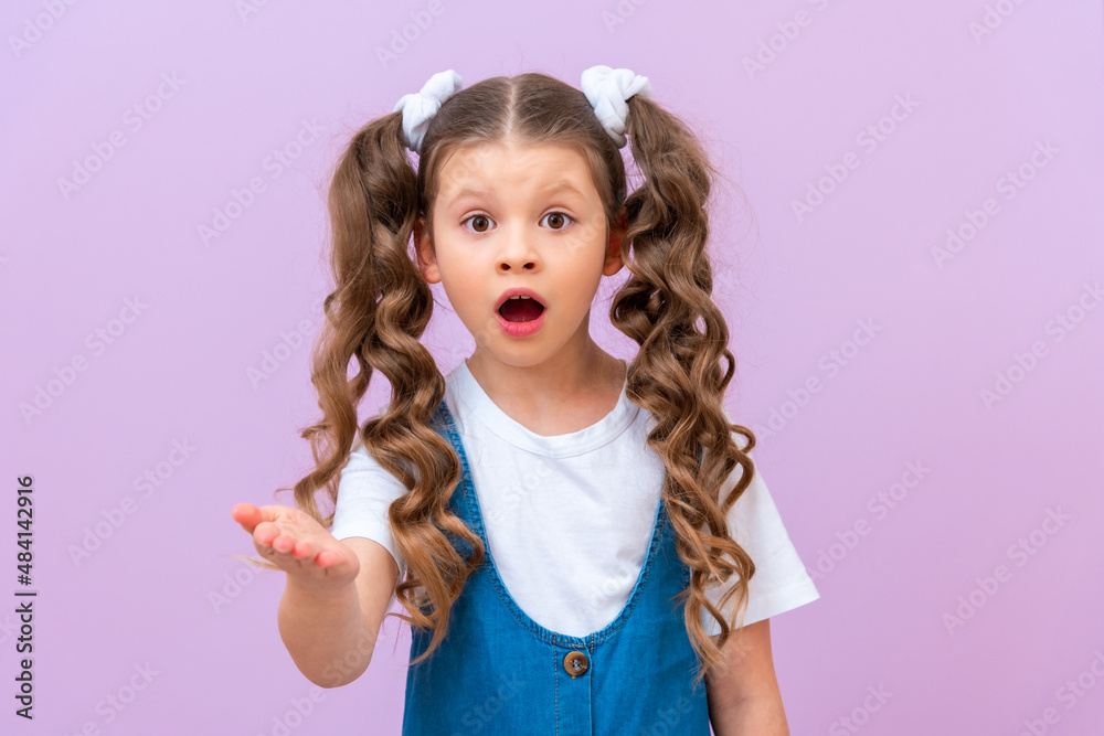 The surprised little girl stretched out her hand forward and asks. A child with long curly hair opened her mouth. The surprised little girl stretched out her hand forward and asks. A child with long curly hair opened her mouth.