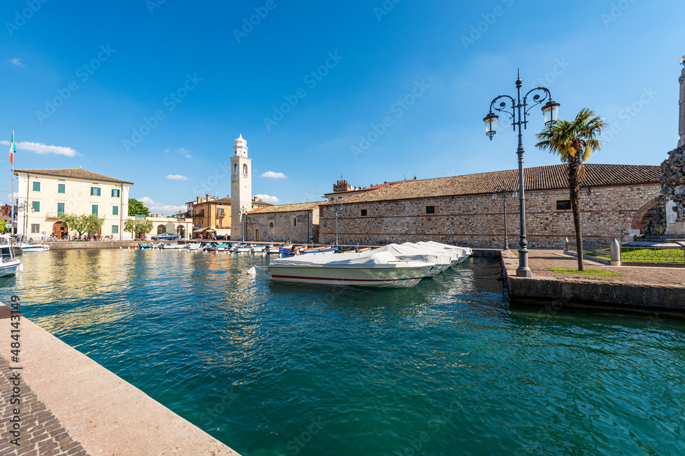 Port of the small village of Lazise, tourist resort on the coast of Lake Garda (Lago di Garda). Ancient church of San Nicolo in Romanesque style. Verona province, Veneto, Italy, southern Europe.