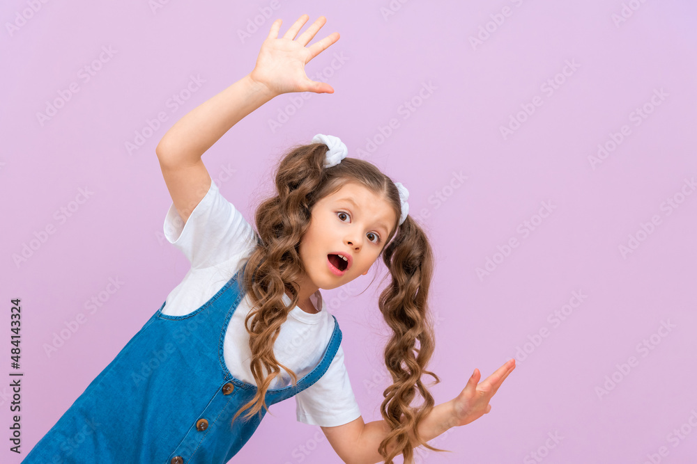 The child looks out from around the corner and rejoices, the child waves his hands in a good mood.