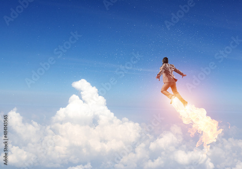 Businessman in suit and aviator hat flying in sky