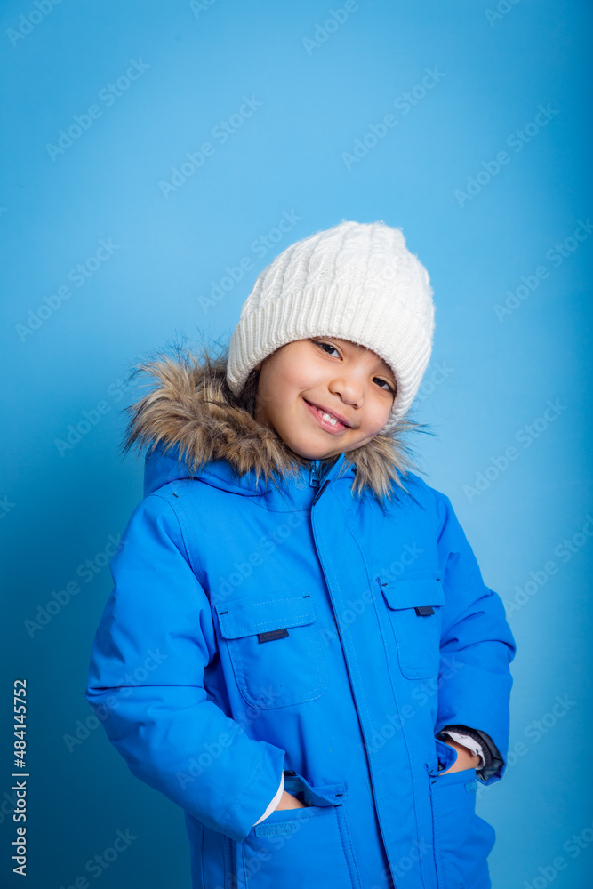 portrait of little Asian girl in blue winter clothes on blue background portrait of little Asian girl in blue winter clothes on blue background