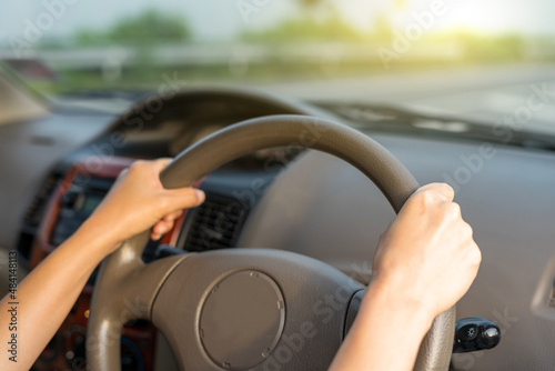 Hand female on the steering wheel of a car while driving the windshield and road. Close up of woman hand presses the horn on the steering wheel on her car.
