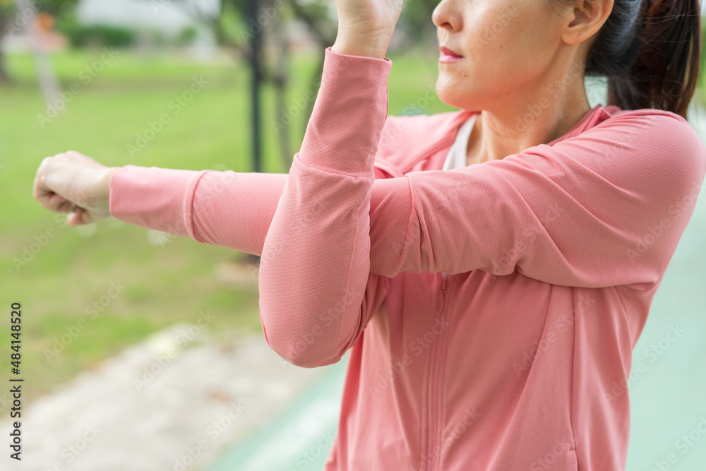 Young asian woman relaxing in sports outfits pink stretching before workout in the park get a healthy lifestyle. Healthy sporty girl warming and stretching arms and looking away. Young asian woman relaxing in sports outfits pink stretching before workout in the park get a healthy lifestyle. Healthy sporty girl warming and stretching arms and looking away.