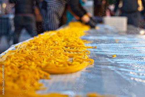 Demonstration of spaghetti production at the fair. Setting a record for the longest pasta in the world. Yellow long pasta stretched on the table. © Ivan