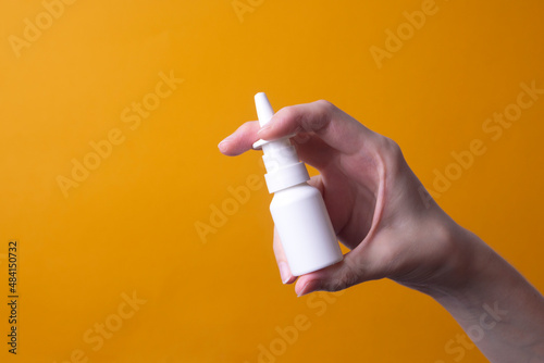 female hand holding nose spray