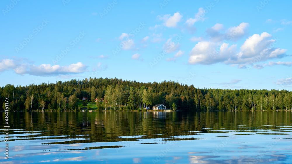 Wunderschöner Blick auf Stukas Ferienhäuser vom See aus in Schweden mit Spiegelungen im Wasser vom Boot aus Im Schwedenurlaub