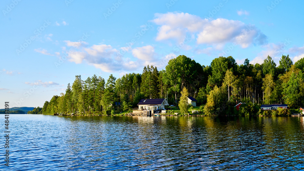Wunderschöner Blick auf Stukas Ferienhäuser vom See aus in Schweden mit Spiegelungen im Wasser vom Boot aus Im Schwedenurlaub