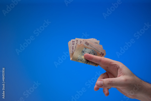 Romanian Lei currency banknotes held by male hand. Close up studio shot, isolated on blue background