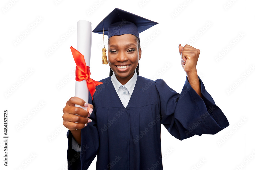 education, graduation and people concept - happy graduate student woman in mortarboard and bachelor gown with diploma celebrating and making winning gesture over white background