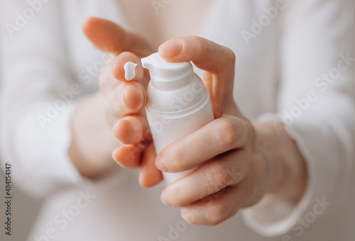 Cream skin care hands. Close-up woman holding cream for hands. Woman applying hand cream. Girl holding tube with skin care product.View from front.