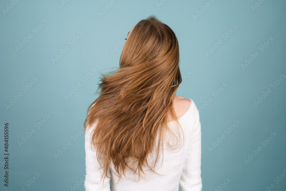 Close beauty portrait of a woman with perfect skin and natural makeup,white soft sweater, moving head shaking hair on a blue background Close beauty portrait of a woman with perfect skin and natural makeup,white soft sweater, moving head shaking hair on a blue background
