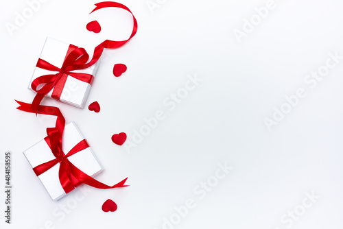 Gift boxes with festive bows and small hearts on a white background. Flat lay, top view, copy space. Valentine's Day banner or greeting card