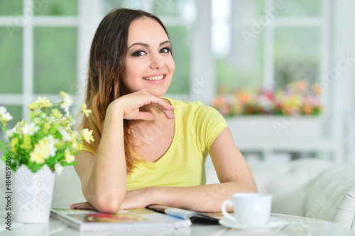 Beautiful young woman with cup of tea reading magazine Free Download Beautiful young woman with cup of tea reading magazine - GFXLoad