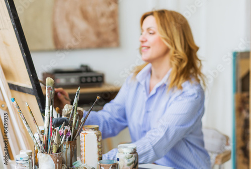 Mature woman painting brush on canvas at studio. photo