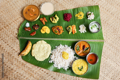 Traditional Onam sadhya rice Sambar, Rasam, parippu dal curry ghee Pappadom Payasam on banana leaf Onam Vishu Pongal Diwali festival vegetarian food Kerala Tamil Nadu South India.