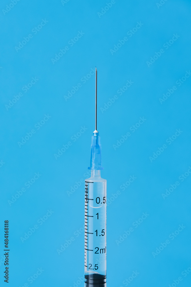 Disposable syringe with a metal needle and on a blue background. Vertical image, place for text. Disposable syringe with a metal needle and on a blue background. Vertical image, place for text.