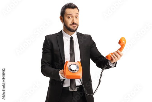 Confused businessman holding an orange rotary phone