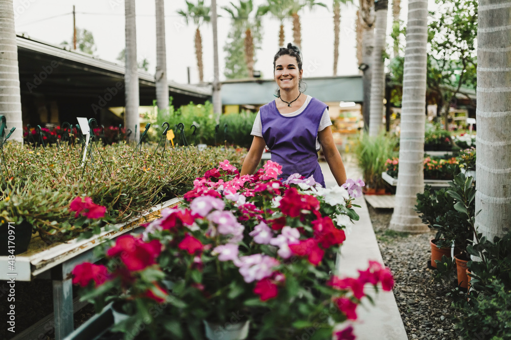 Smiling female entrepreneur with flowering plants at garden center