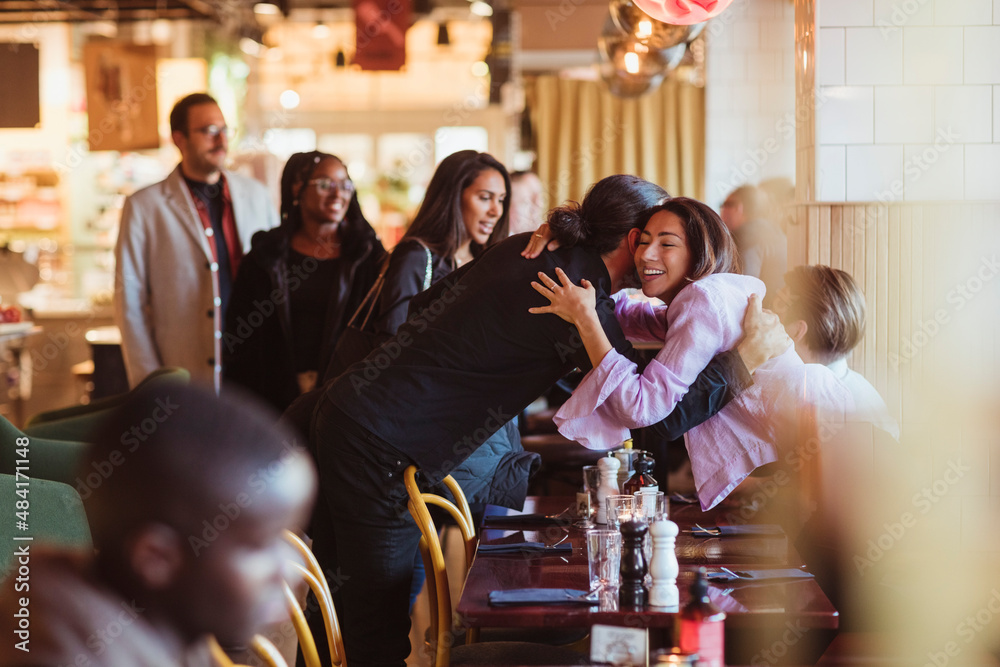 Multiracial male and female friends greeting at restaurant afterwork Multiracial male and female friends greeting at restaurant afterwork