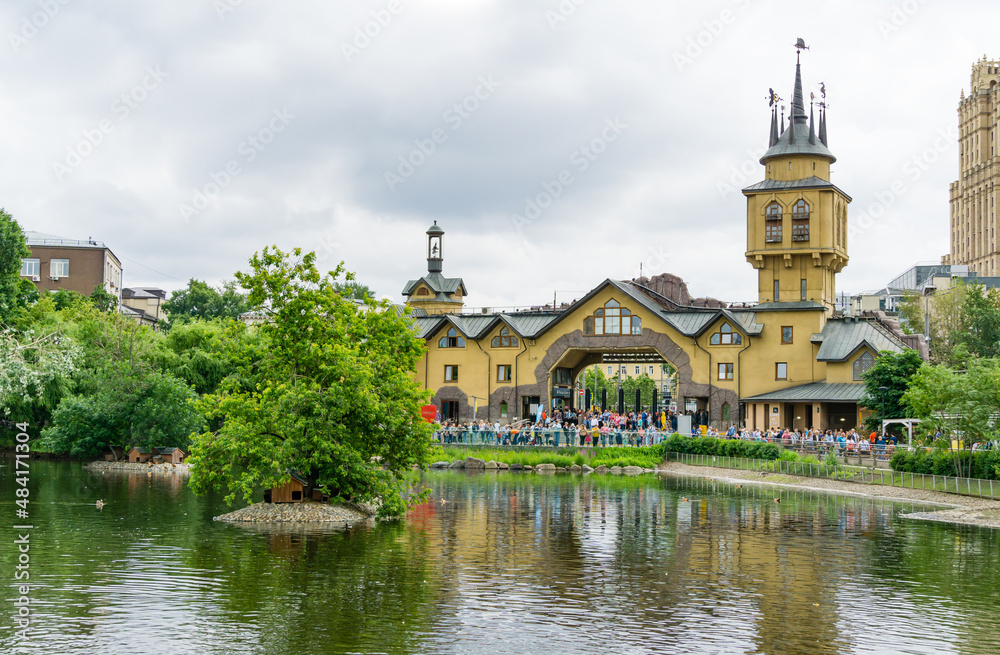 View of main entrance of the Moscow zoo thru pond. A lot of people with children at the entrance. Moscow, Russia - June 16, 2019