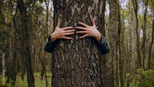 Arms Hugging a Tree In a Forest, showing Love and Care for Nature and Environment of Earth. Hug the tree. Hands of a adult person hug a tree trunk. Unity with nature, environmental protection