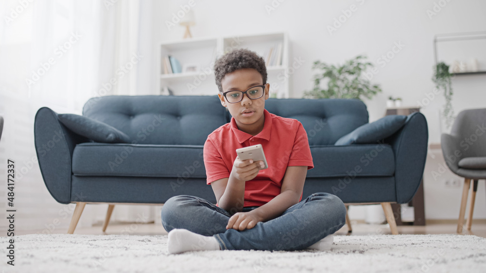 Bored African American boy scrolling smartphone, staying home during lockdown Bored African American boy scrolling smartphone, staying home during lockdown