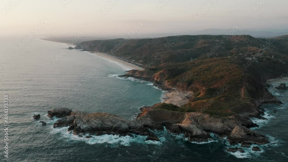 Aerial backwards shot of beautiful Punta Cometa viewpoint and Mazunte Beach with coastline in background during foggy sunset in Mexico Aerial backwards shot of beautiful Punta Cometa viewpoint and Mazunte Beach with coastline in background during foggy sunset in Mexico