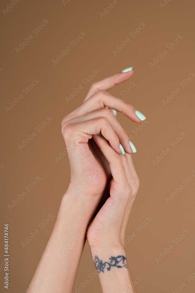 Graceful female hands with thin long fingers and mint turquoise manicure on a beige background Graceful female hands with thin long fingers and mint turquoise manicure on a beige background