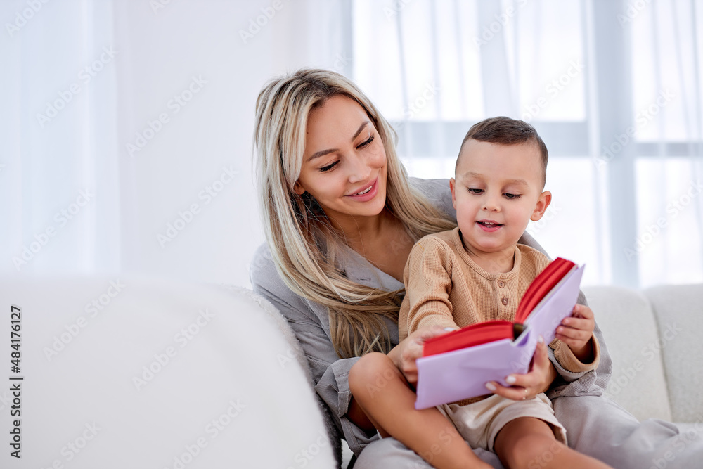 friendly family young mother babysitter hold read book relax embrace cute little child boy, smiling parent mum tell small kid funny fairy tale story sit on sofa having fun together at home friendly family young mother babysitter hold read book relax embrace cute little child boy, smiling parent mum tell small kid funny fairy tale story sit on sofa having fun together at home