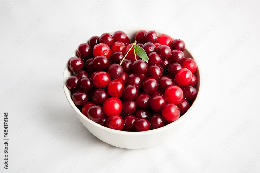 white plate with red cherry on light background white plate with red cherry on light background