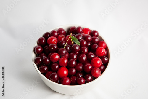 white plate with red cherry on light background