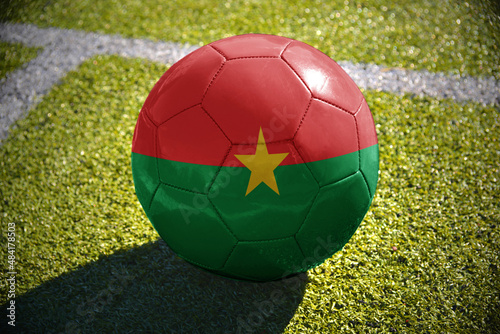 football ball with the national flag of burkina faso lies on the green field