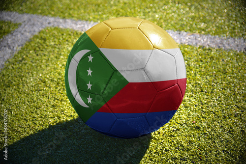 football ball with the national flag of comoros lies on the green field