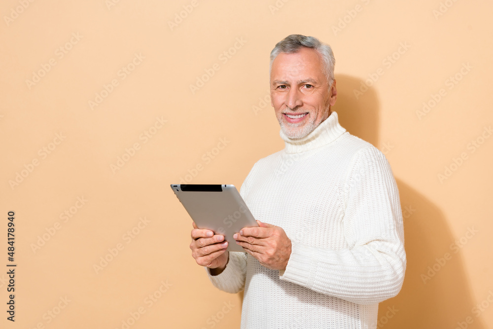 Portrait of attractive cheerful grey-haired man using device blogging app smm isolated over beige pastel color background Portrait of attractive cheerful grey-haired man using device blogging app smm isolated over beige pastel color background