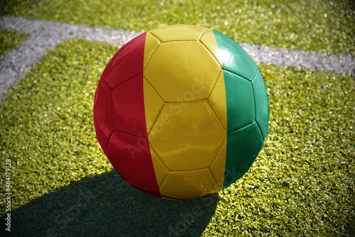 football ball with the national flag of guinea lies on the green field
