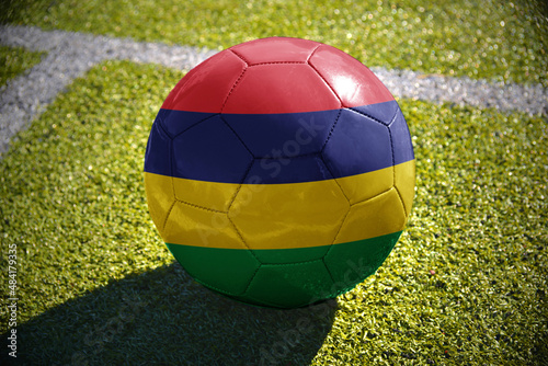 football ball with the national flag of mauritius lies on the green field