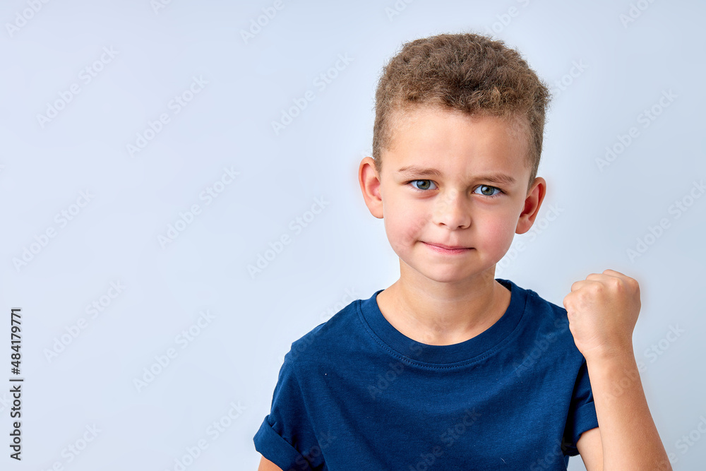 handsome boy looks angry. The child is offended, threatens, shows a fist. Angry, resentful, aggressive child. Portrait on white studio background. Children's human emotions concept handsome boy looks angry. The child is offended, threatens, shows a fist. Angry, resentful, aggressive child. Portrait on white studio background. Children's human emotions concept