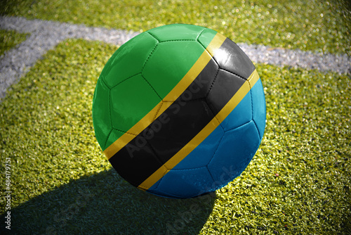 football ball with the national flag of tanzania lies on the green field