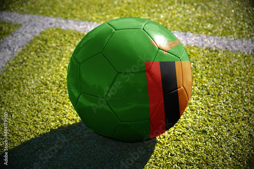 football ball with the national flag of zambia lies on the green field