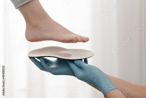 Orthopedic insole on a white background. Hands in rubber gloves hold an orthopedic insole. Foot care, comfort for the feet. Doctor orthopedist tests the medical device. Flat feet correction
