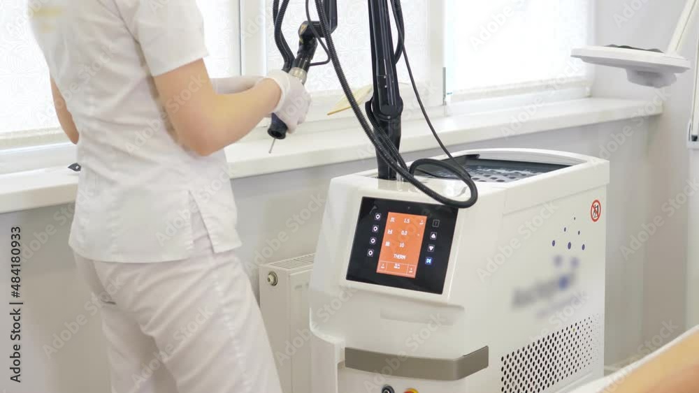 Cosmetologist dermatologist adjusts a modern laser in a beauty salon. Hardware laser hair removal.Clinic of aesthetic Medicine.Laser pulses cleanse the skin.Hardware cosmetology. Cosmetologist dermatologist adjusts a modern laser in a beauty salon. Hardware laser hair removal.Clinic of aesthetic Medicine.Laser pulses cleanse the skin.Hardware cosmetology.