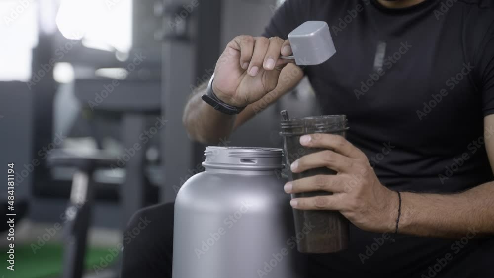 close up shot of bodybuilder hands taking protein powder and mixing with water on bottle by shaking at gym - concpet of muscular gain, nutritional supplement and wellness close up shot of bodybuilder hands taking protein powder and mixing with water on bottle by shaking at gym - concpet of muscular gain, nutritional supplement and wellness