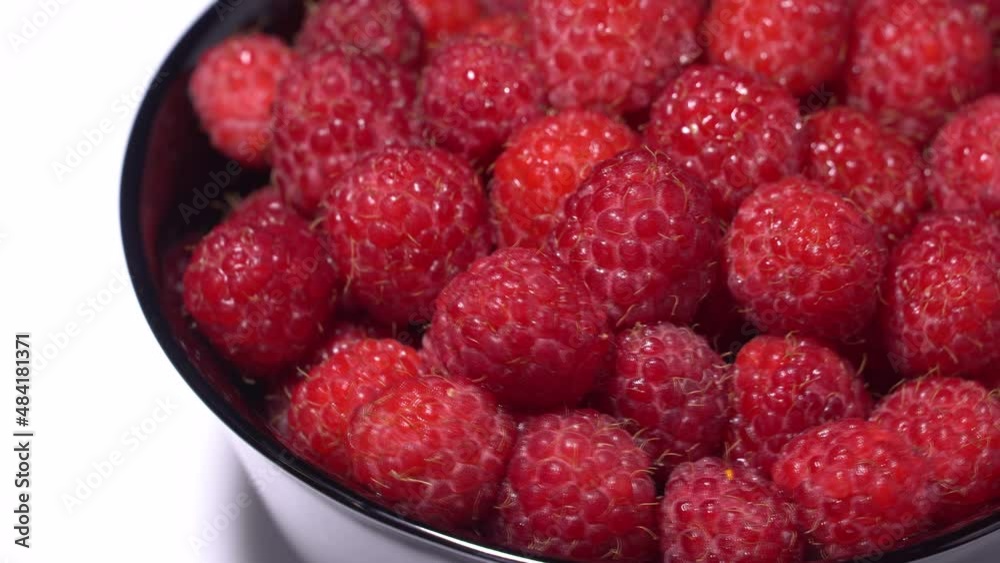 Fresh juicy red raspberries in a black bowl, rotation background. Close up Fresh juicy red raspberries in a black bowl, rotation background. Close up
