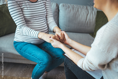 Pregnant support group meetup in a house. Supporting patient. Psychologist hold hands of girl patient, close up. Abortion decision. Psychological therapy, survive personal crisis