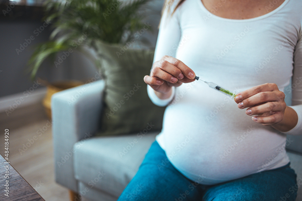 Unrecognizable pregnant woman with syringe in hand. Woman making